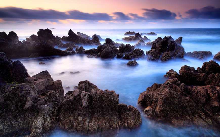 日出时分海岸礁石群柔光海面云层粉紫天空静谧景色电脑壁纸