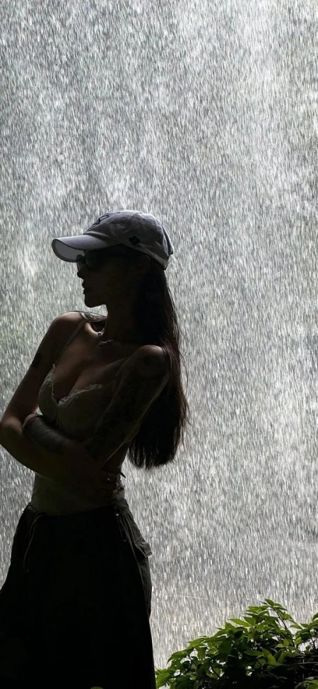 雨幕中戴帽墨镜女子侧身剪影手机壁纸