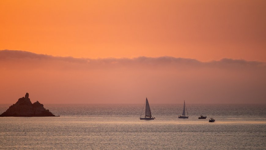 黄昏海面帆船与礁石宁静唯美风景电脑壁纸