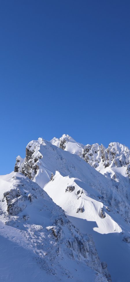 雪山峰顶积雪覆盖蓝天映衬壮丽风景手机壁纸