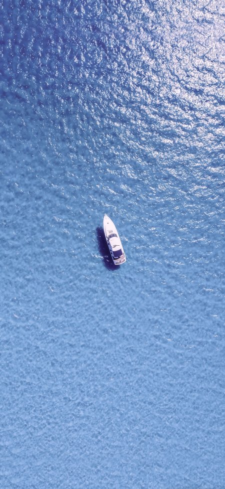 白色游艇漂浮在蓝色海面上的航拍风景手机壁纸