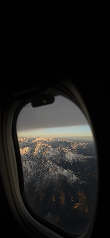 飞机舷窗俯瞰金色雪山山脉壮丽风景手机壁纸