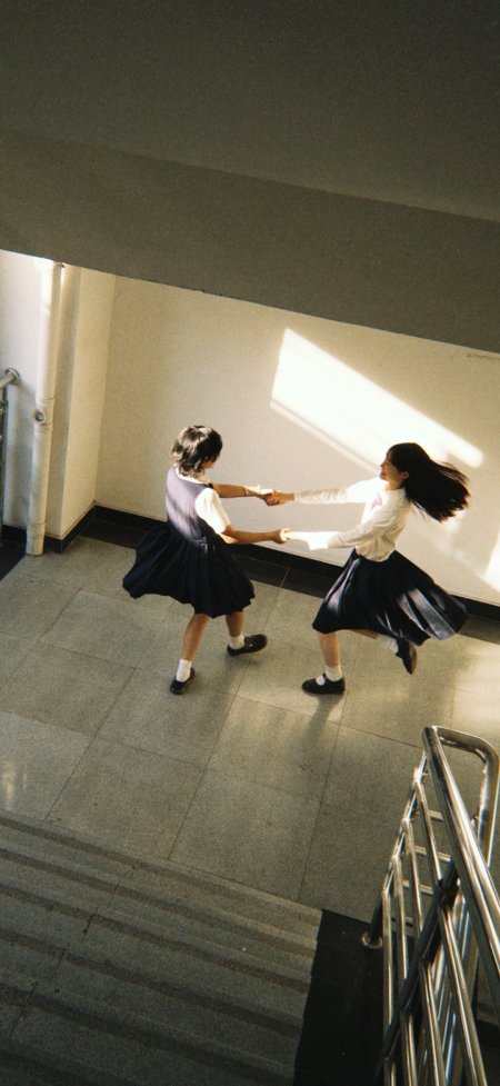 两位少女穿校服牵手在楼梯间跳舞人物手机壁纸