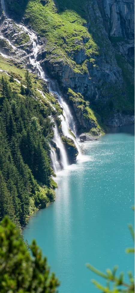 瑞士阿尔卑斯山瀑布倾泻入碧绿湖水森林环绕自然风景手机壁纸