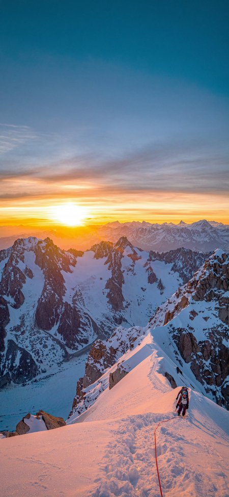 登山者攀登雪山之巅日出金光洒满峰顶壮丽风景手机壁纸