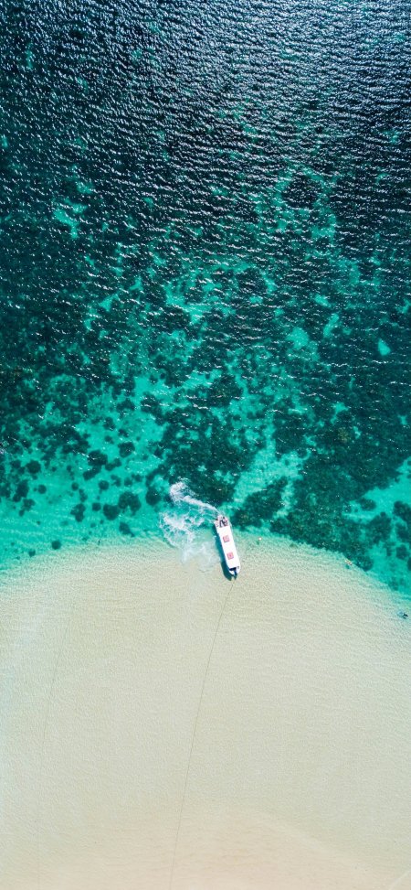 航拍海岛青绿浅滩白色游艇珊瑚礁风景手机壁纸