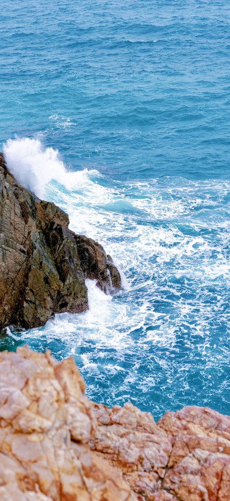 蔚蓝海浪拍打褐色海岸礁石俯拍自然风景手机壁纸