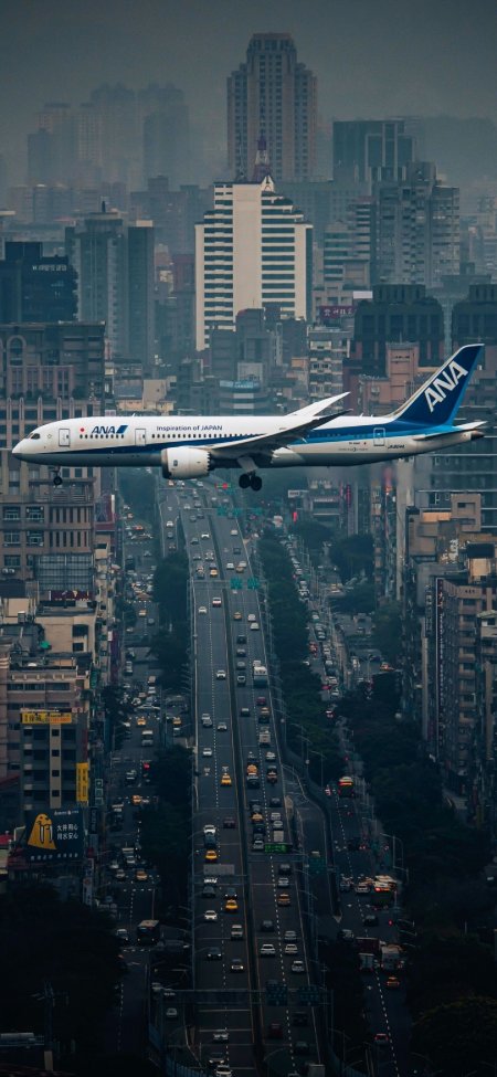 客机低空掠过城市公路风景手机壁纸