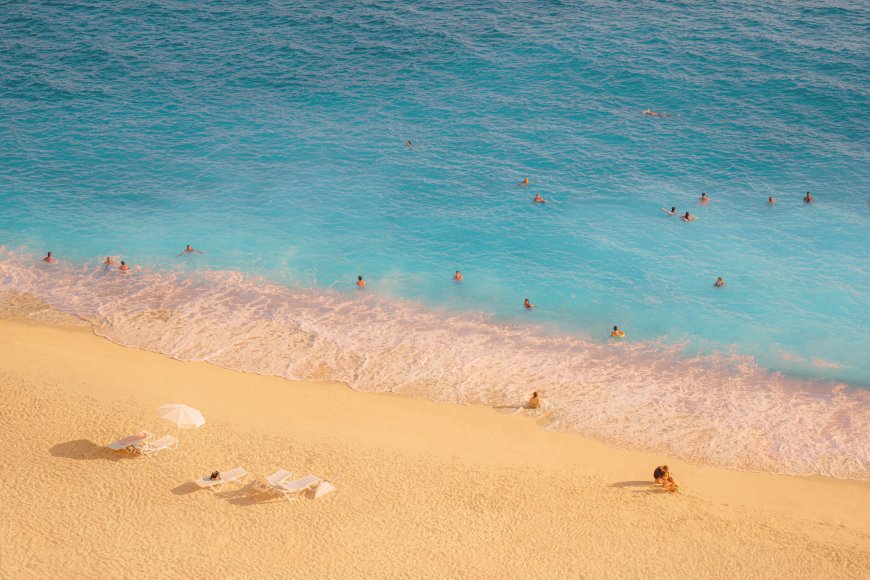俯拍碧蓝海水金色沙滩游泳人群躺椅海滨风景电脑壁纸