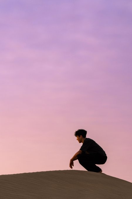 沙漠少年蹲坐沙丘粉紫人文风土手机壁纸