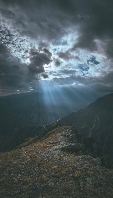 山峰云隙光束穿透蓝灰风景手机壁纸