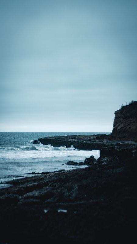 海浪拍岸礁石嶙峋蓝灰风景手机壁纸