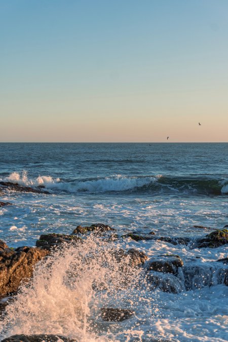 海浪拍礁夕阳余晖蓝白风景手机壁纸