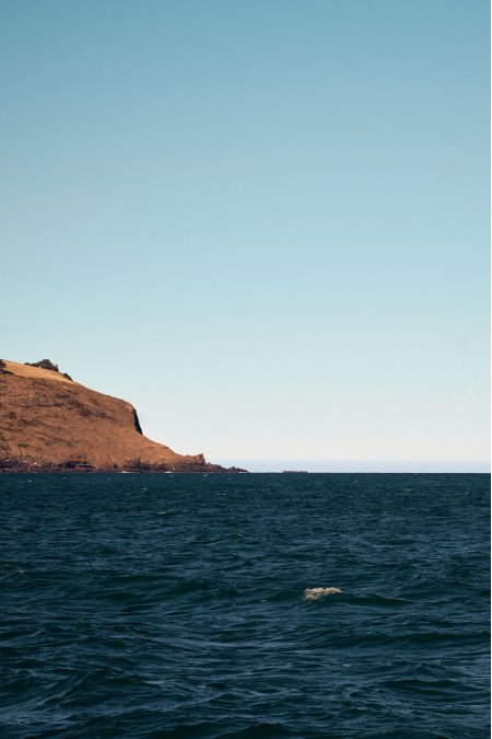 海面波光崖岸矗立蓝白风景手机壁纸