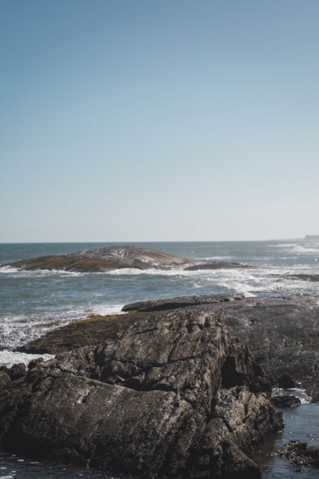 海岸礁石浪花拍打蓝白风景手机壁纸