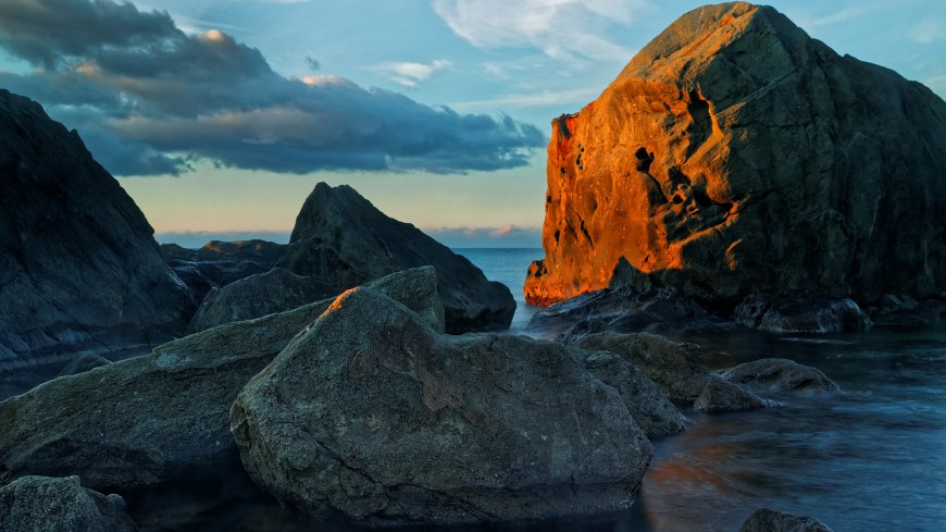 海边巨岩夕阳映照橙蓝自然风景电脑壁纸