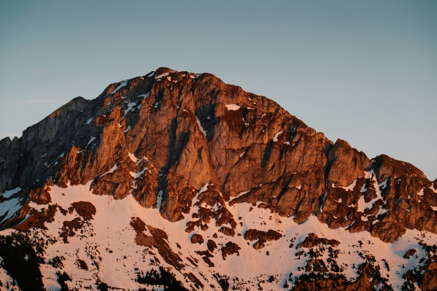 雪山巍峨岩壁嶙峋雪覆山脊暖金自然风景电脑壁纸
