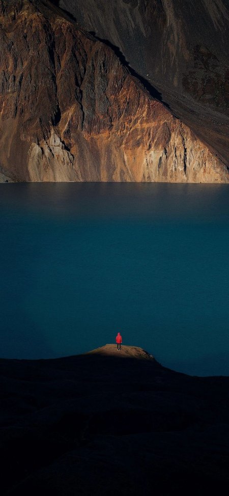 高原湖泊孤影红衣旅人深蓝静谧风景手机壁纸