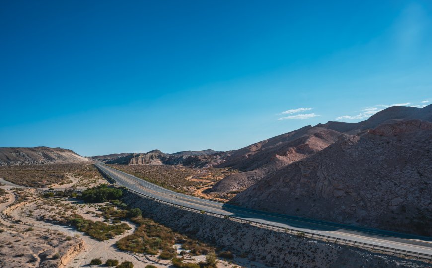 荒漠公路蜿蜒穿行棕褐山峦蓝空风景电脑壁纸