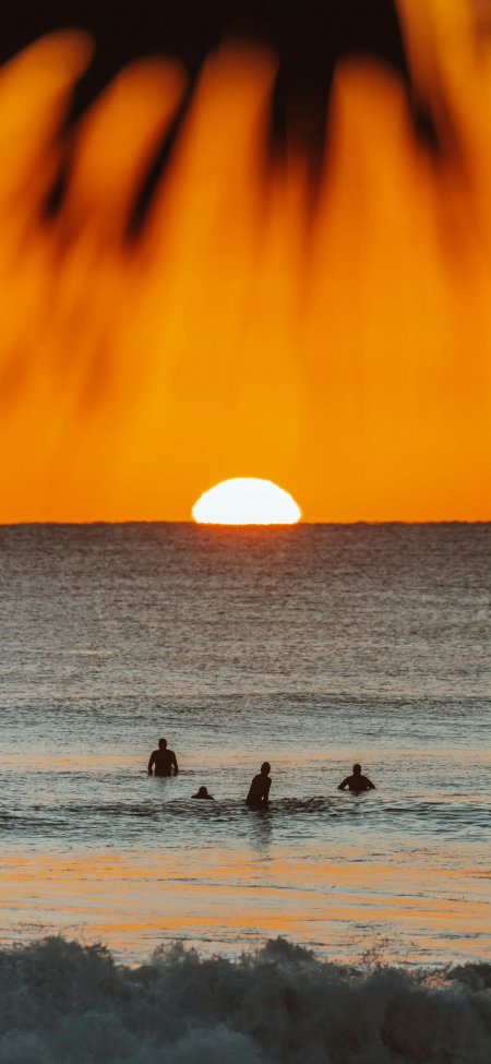 海边日落四人冲浪剪影暖橙自然风景手机壁纸
