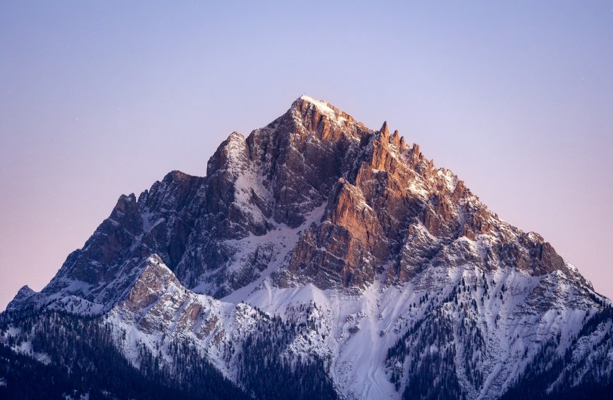 雪山巍峨峰顶积雪岩壁裸露紫蓝渐变天空自然风景电脑壁纸