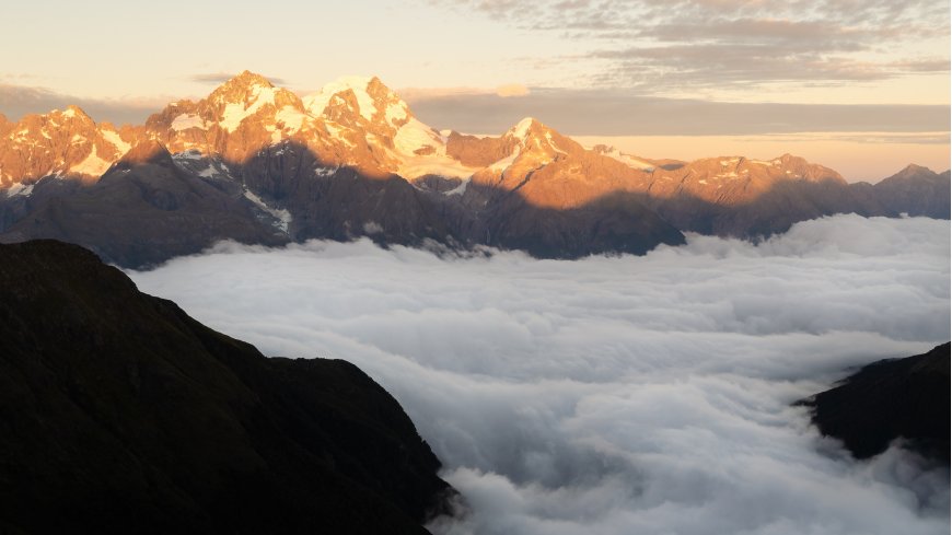 雪山巍峨云海翻涌金橙暖调风景电脑壁纸