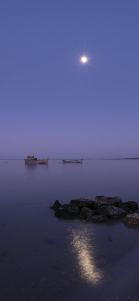 月夜海面两艘小船静泊岩石岸边蓝紫风景手机壁纸