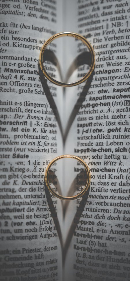 金色婚戒叠放书页心形阴影暖灰静物特写手机壁纸