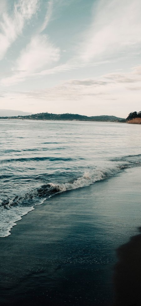 海浪轻拍黑沙滩远山云影蓝灰调自然风景手机壁纸