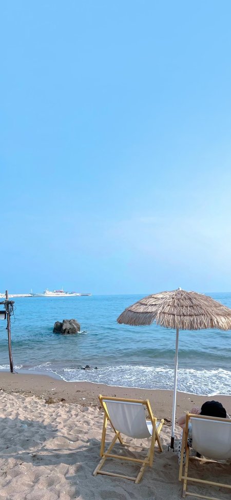 海边沙滩躺椅草伞远航轮船蓝白风景手机壁纸
