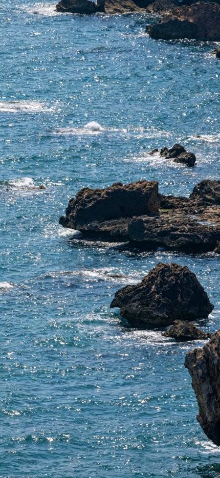 蔚蓝海面波光粼粼礁石嶙峋自然风景手机壁纸